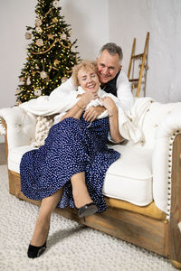 Portrait of loving senior couple sitting on sofa at home
