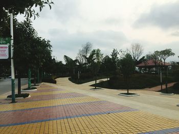 Empty sidewalk by buildings in city against sky