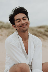 Portrait of smiling young man sitting on beach