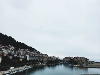 Buildings by river against sky in city