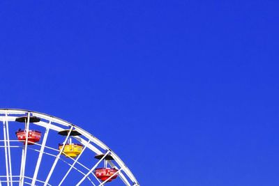 Low angle view of ferris wheel against blue sky