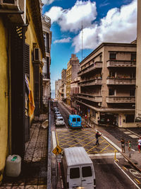 Vehicles on road amidst buildings in city against sky