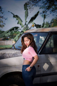 Portrait of woman standing against car