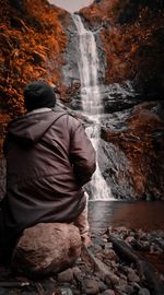 Rear view of man looking at waterfall