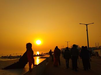 Silhouette people against orange sky during sunset