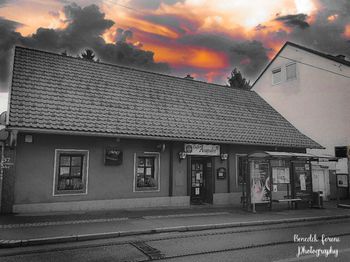 Building by street against sky at sunset