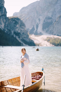 Portrait of woman standing on lake against mountains