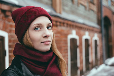 Portrait of beautiful young woman wearing knit hat and scarf outdoors