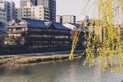 Buildings by river in city against sky