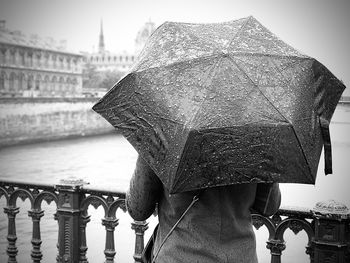 Low angle view of wet railing against river in city