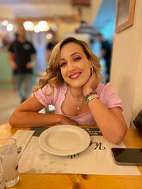 Portrait of smiling friends sitting on table