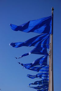 Low angle view of flags against blue sky