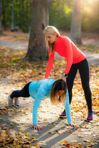 Personal fitness trainer using smart watch during training in the park. woman doing plank.