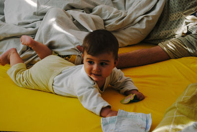 High angle view of baby lying on bed with father at home