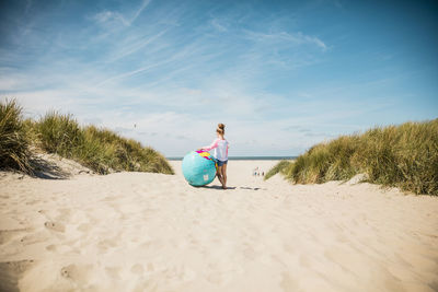 Full length of woman sitting on beach against sky