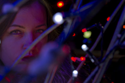 Close-up portrait of woman holding illuminated lights at night