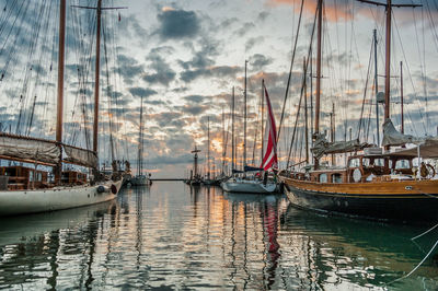 Sailboats moored in harbor against sky