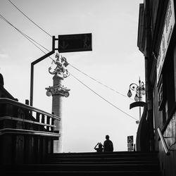 Low angle view of men sitting on staircase against buildings