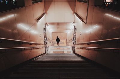 Rear view of woman walking on illuminated subway
