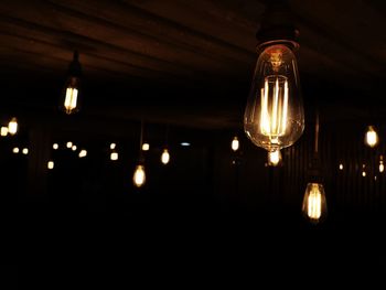 Low angle view of illuminated light bulbs hanging from ceiling