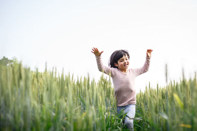 Close view of girl with short hair in pink top run happily in green wheat field