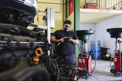 Mechanic adjusting impact wrench at workshop