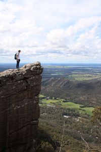 Man standing on rock against sky