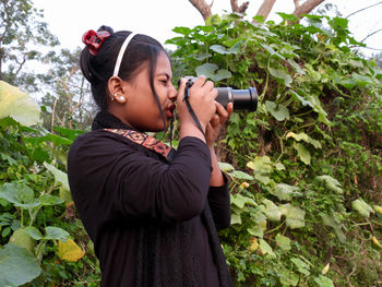 Side view of woman photographing through camera