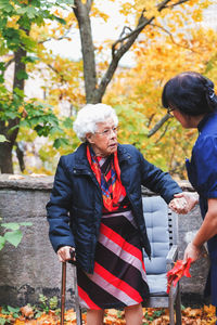 Caretaker assisting senior woman in park