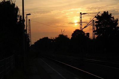 Silhouette railroad tracks against sky during sunset