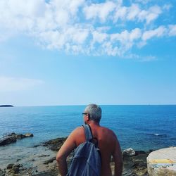 Rear view of man looking at sea against sky
