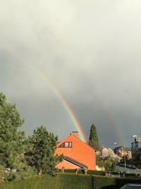 Rainbow over buildings and houses against sky