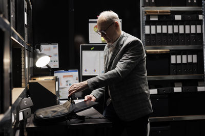 Side view of man using laptop while standing in office