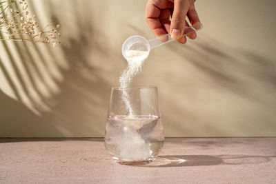 Close-up of hand holding glass on table