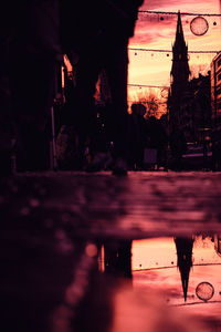 Silhouette person walking on wet street at night
