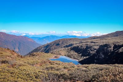 Scenic view of landscape and mountains against blue sky