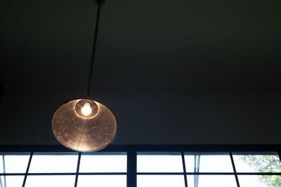 Low angle view of illuminated pendant light hanging from ceiling