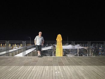 Man standing on railing against sky at night