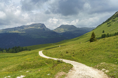 Scenic view of road amidst field against sky