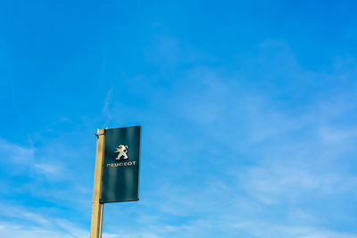 Low angle view of road sign against blue sky