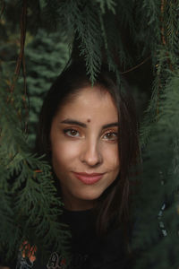 Portrait of beautiful young woman against plants