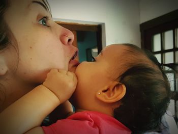 Close-up of mother with baby on bed at home