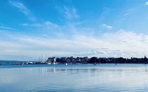 City at waterfront against cloudy sky