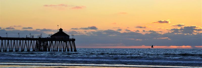 Silhouette pier over sea against sky during sunset