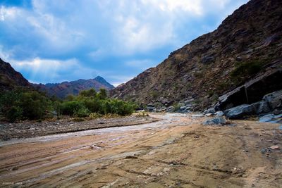 Scenic view of road by mountains against sky