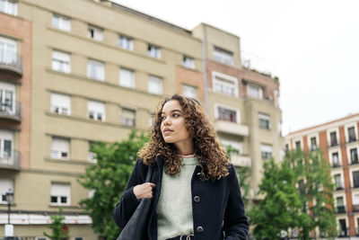 Portrait of beautiful woman standing against buildings