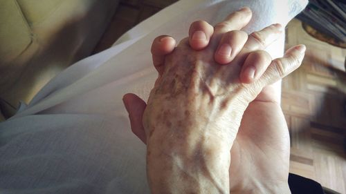 Close-up of person and senior woman holding hands