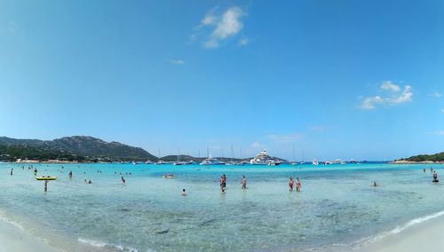 Group of people in sea against blue sky during summer