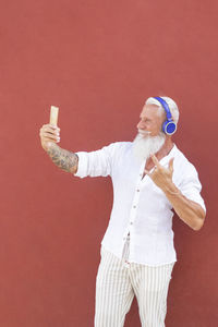 Man holding umbrella standing against red wall