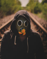 Portrait of person wearing mask on railroad track
